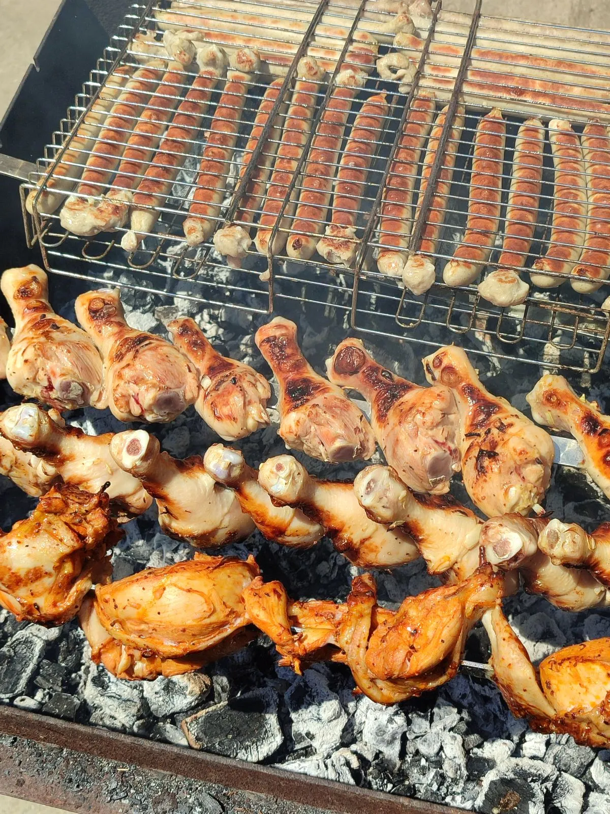 Hähnchenunterkeulen und Würste auf dem Grill