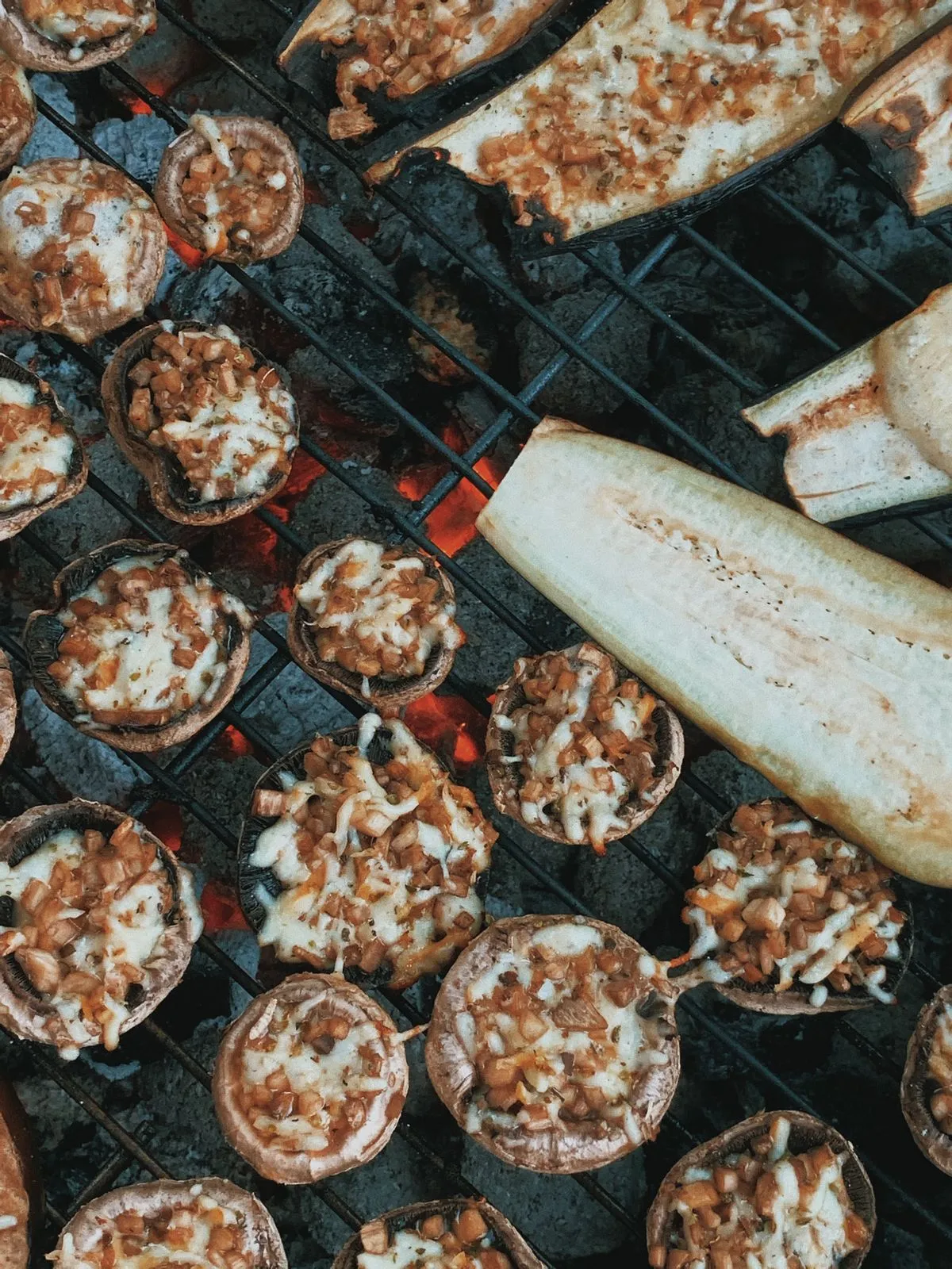 Gefüllte Pilze neben Auberginen auf dem Grill