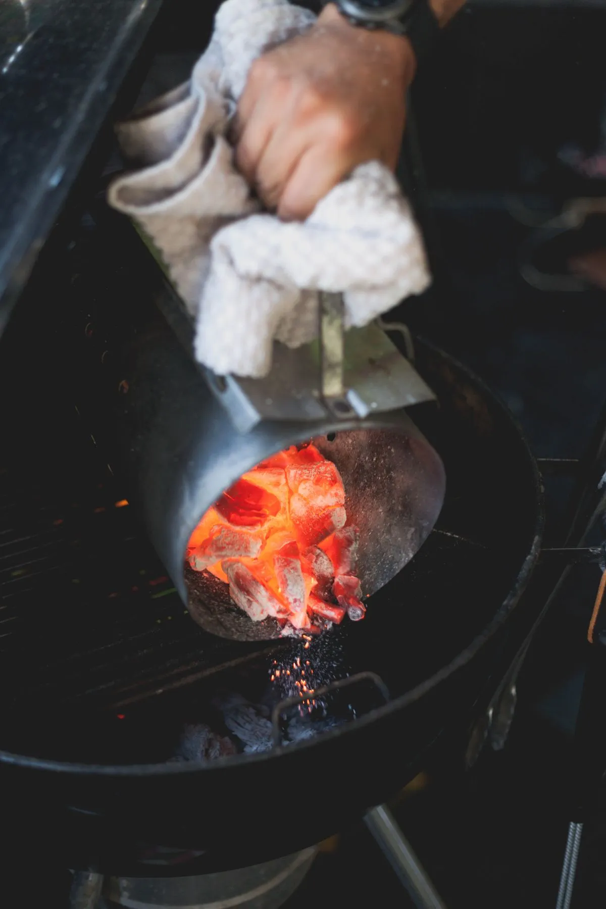 Holzkohle wird in einen Außengrill geschüttet